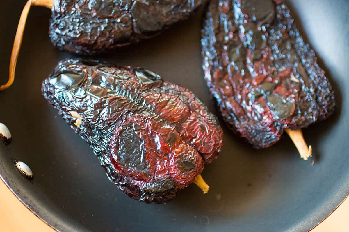 Toasting the ancho peppers in a skillet.