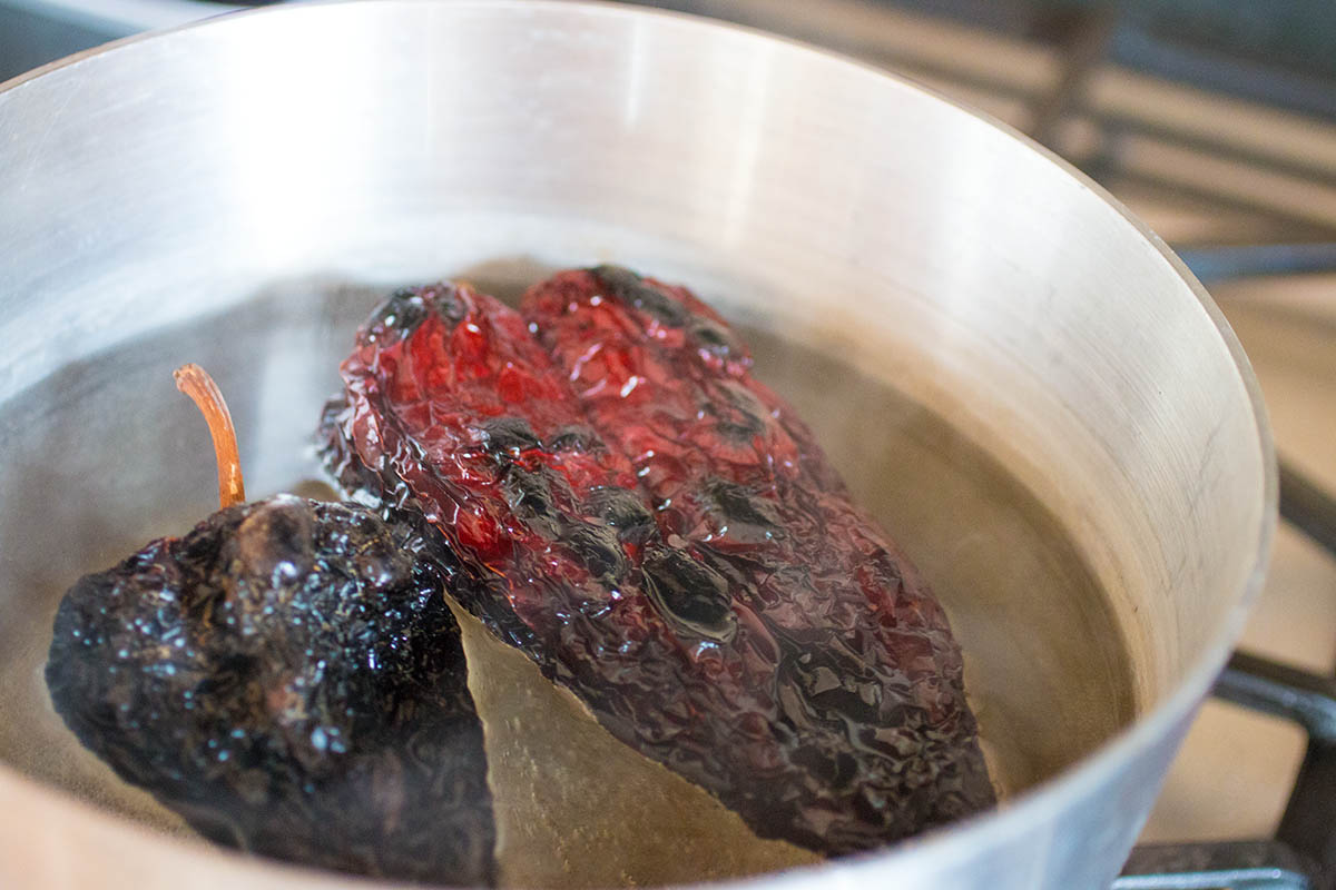 Soaking the ancho peppers in hot water to rehydrate them.