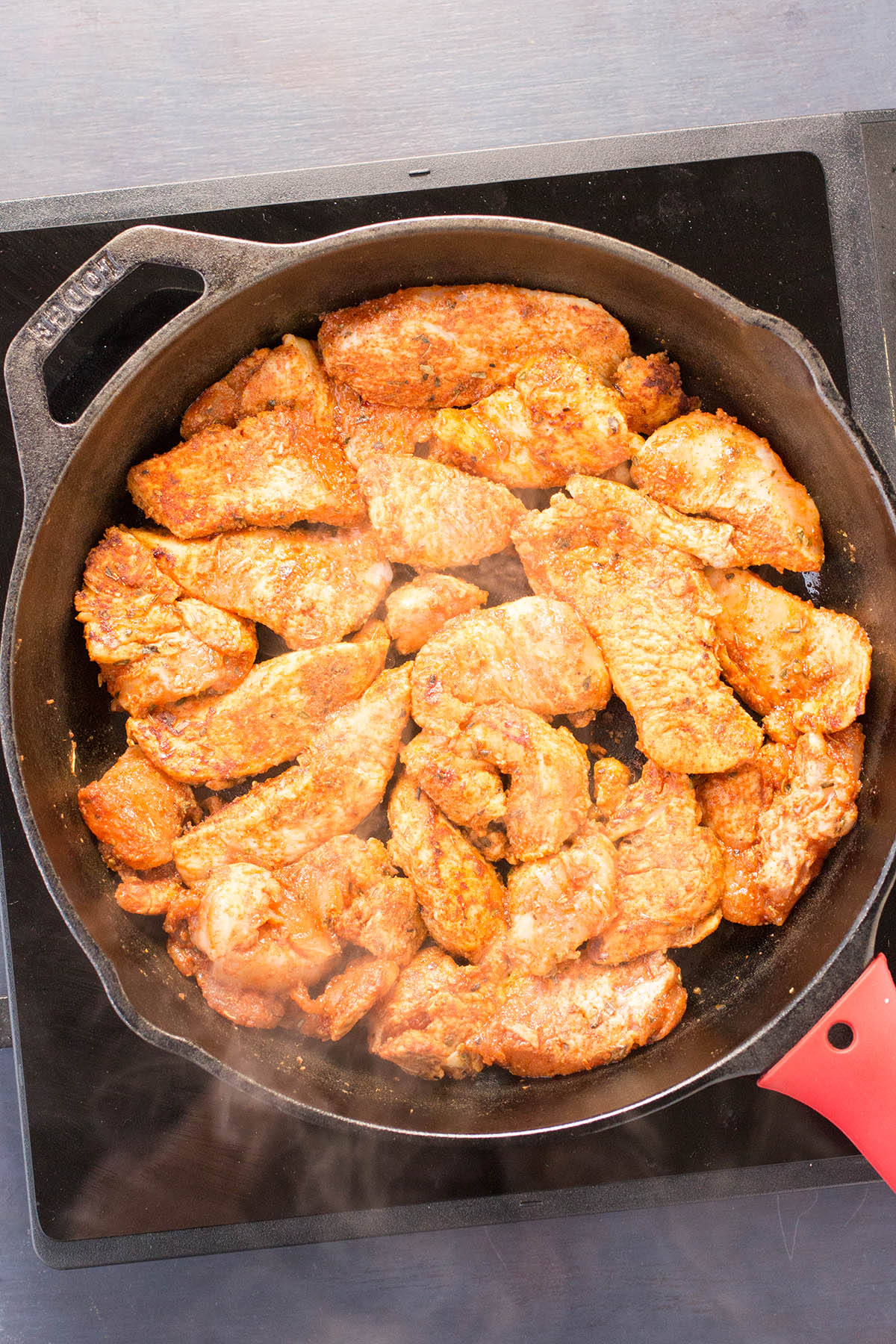 Searing sliced chicken breast in oil.
