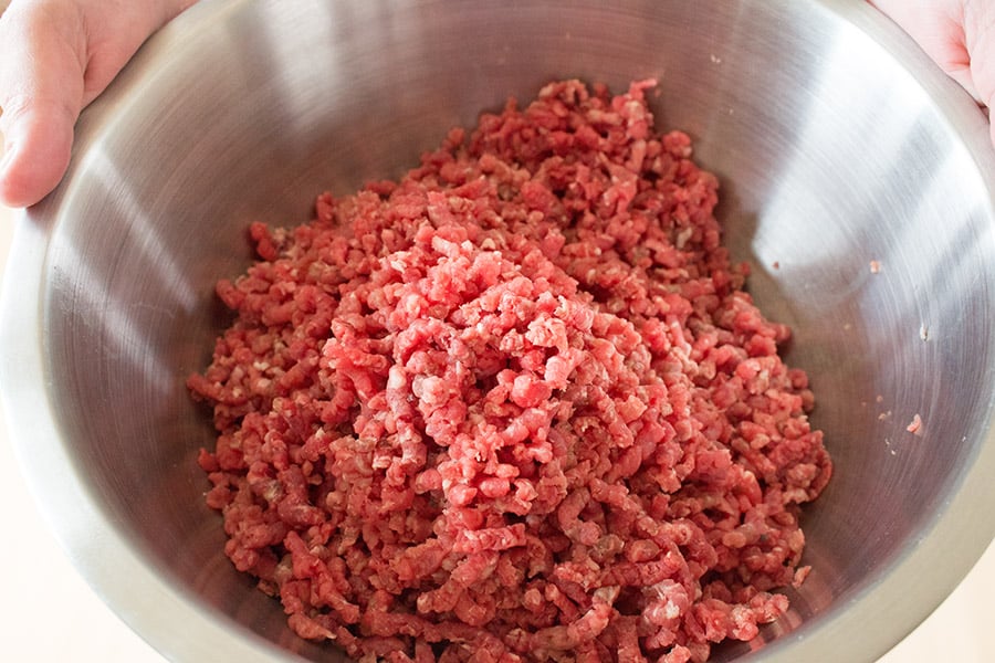 Ground meat in a big metal bowl.