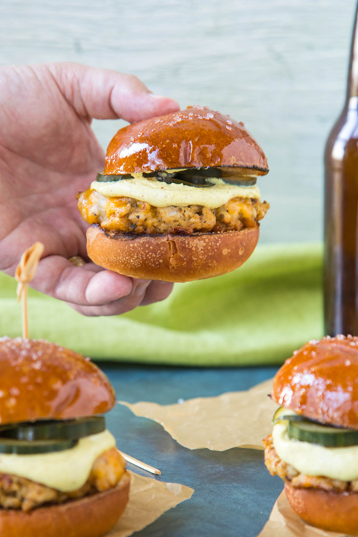 Holding one of the Ground Pork Sliders with Mustard Cream and Quick Pickled Cucumbers