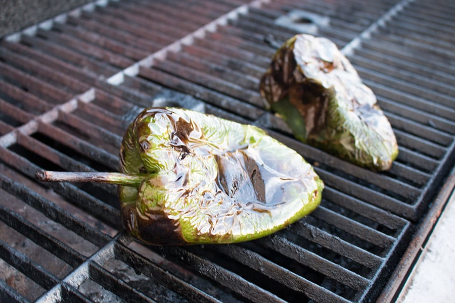 Grilling poblano peppers on a grill outside.