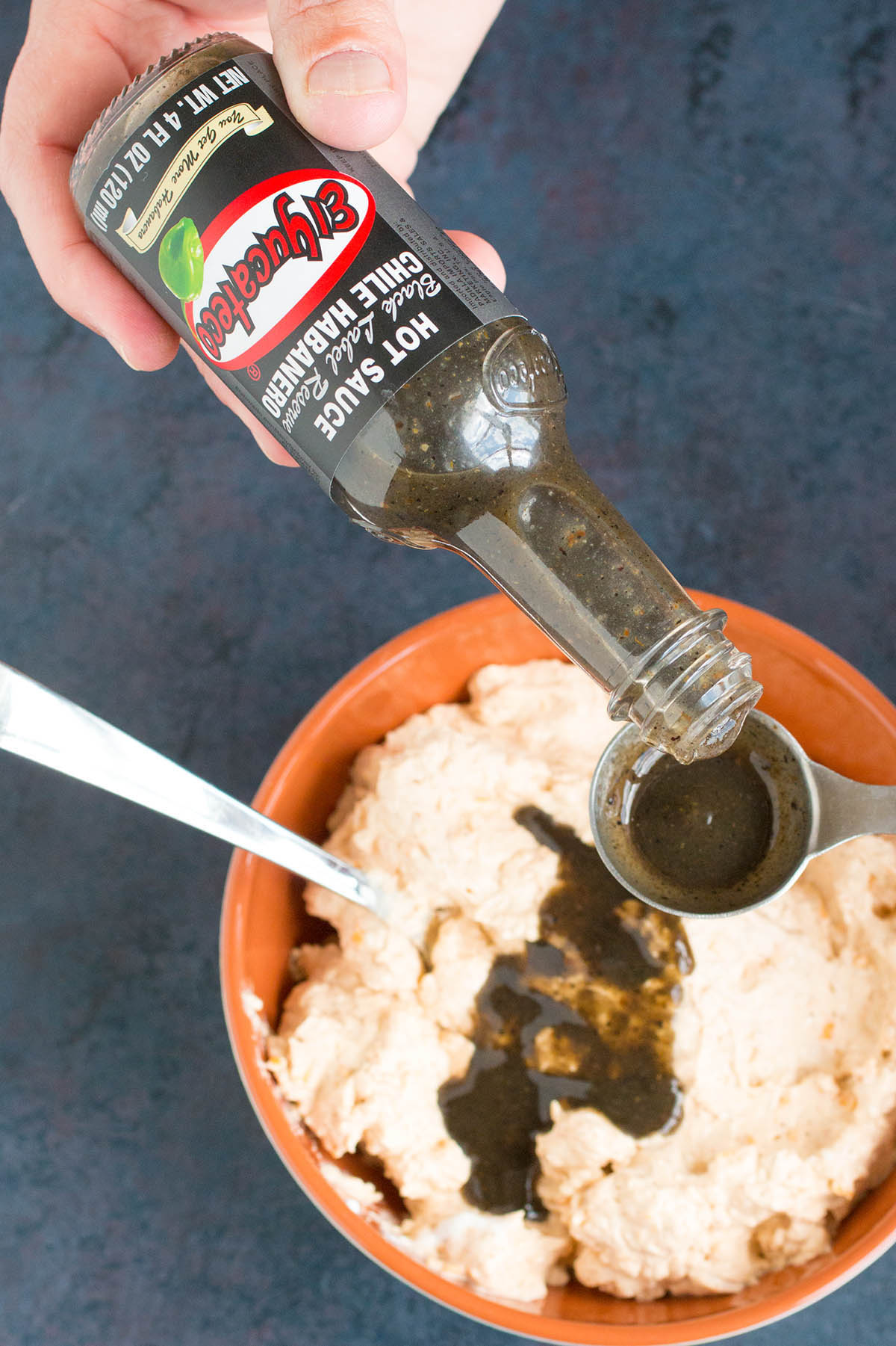 Pouring hot sauce chile habanero from a bottle.