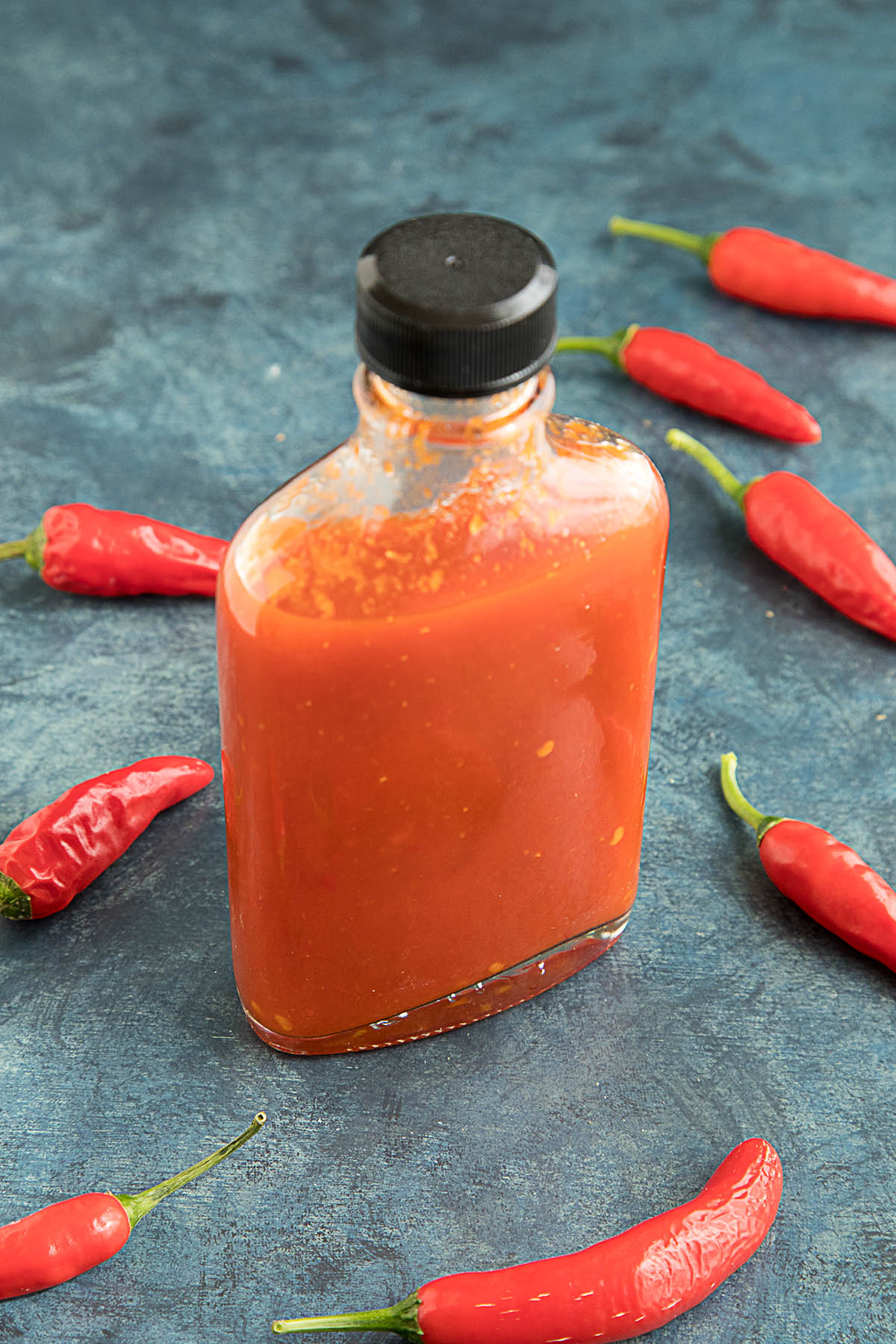 Homemade Louisiana Hot Sauce with plenty of peppers around the bottle
