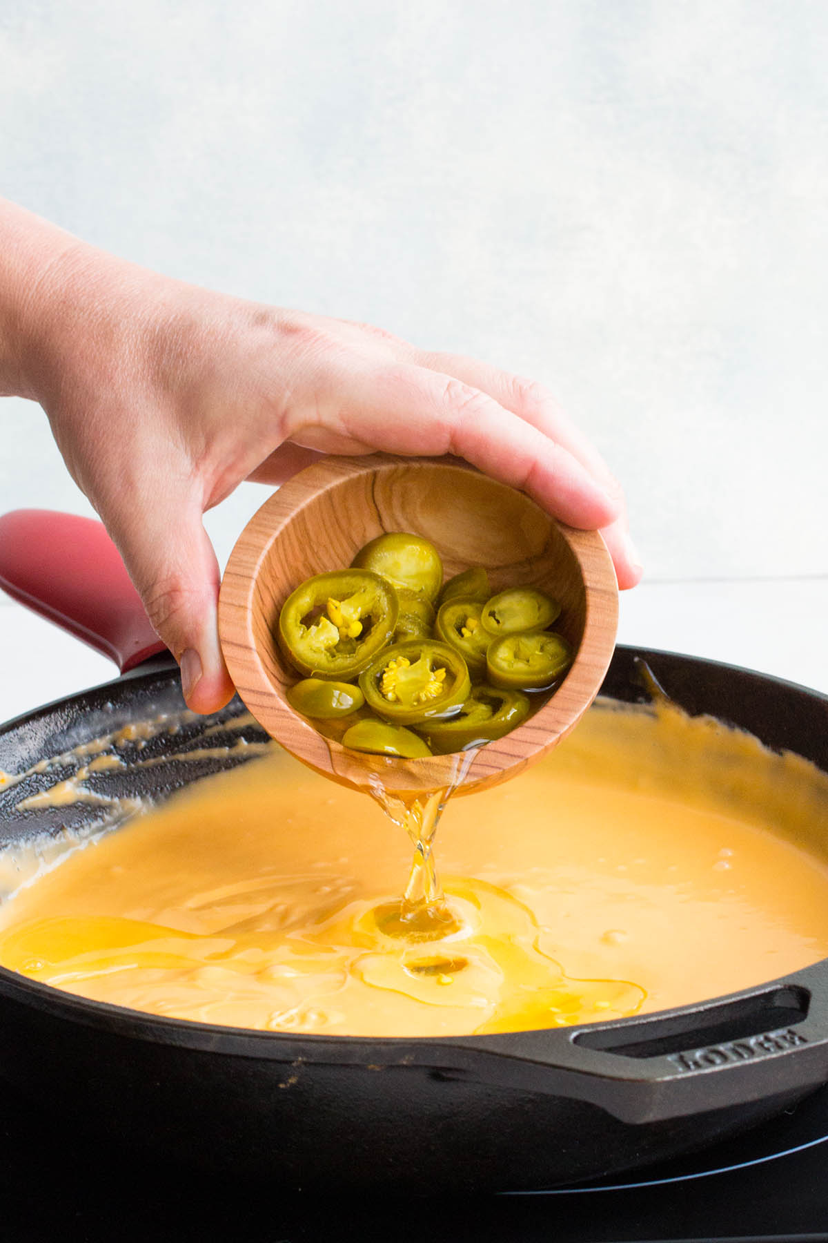 Pouring the Jalapeno Brine into the nacho cheese.