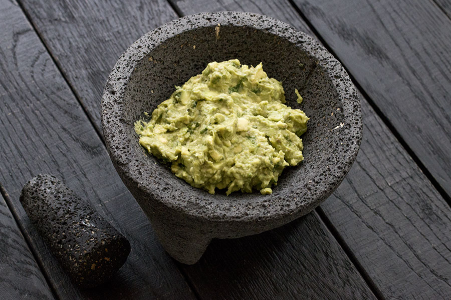 A Molcajete with guacamole in it.