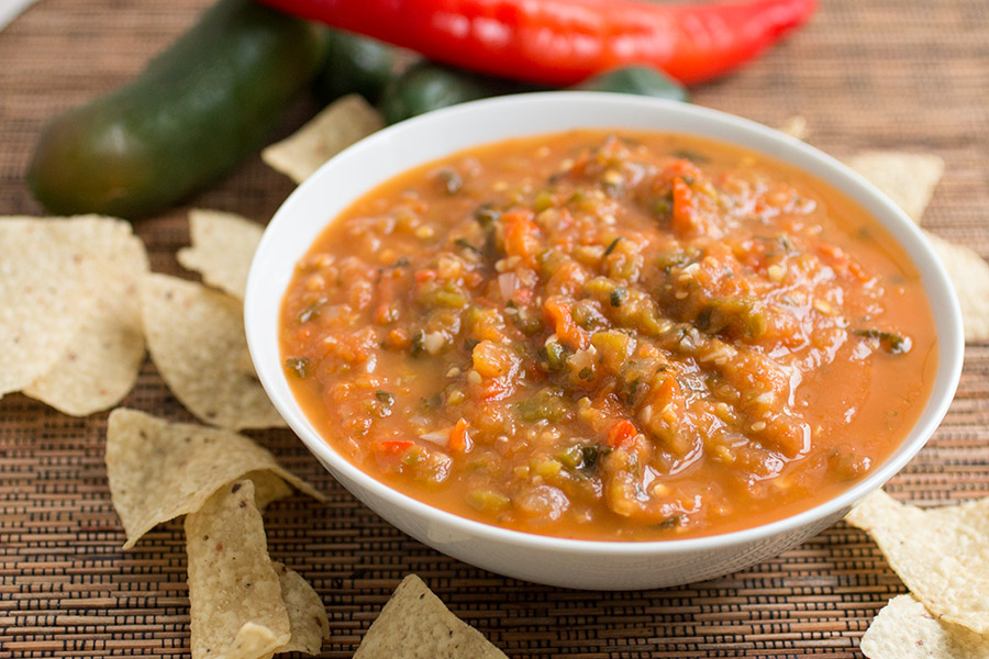 Papaya salsa served in a white bowl with corn chips around it