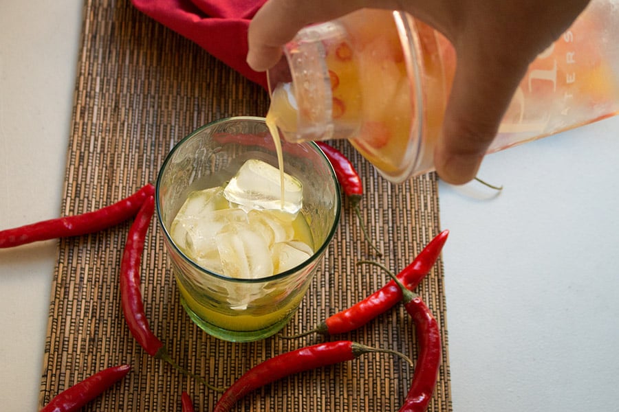 Pouring the Chili Infused Pineapple Vodka Cocktail into a glass.