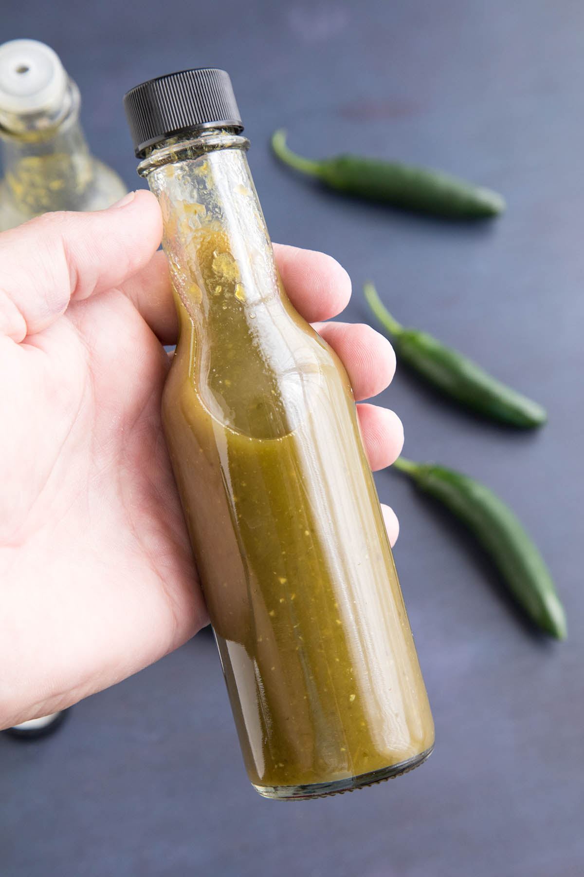 Holding a bottle of the homemade Spicy Serrano Hot Sauce