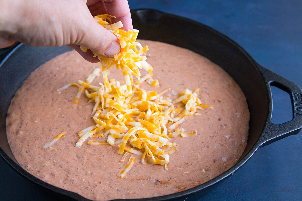 Adding cheese when making Easy Cheesy Chipotle Bean Dip.