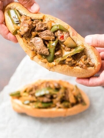 Holding one of the two served Mexi Cheesesteak Sandwiches