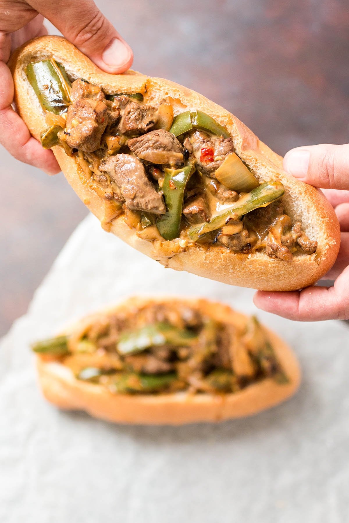 Holding one of the two served Mexi Cheesesteak Sandwiches