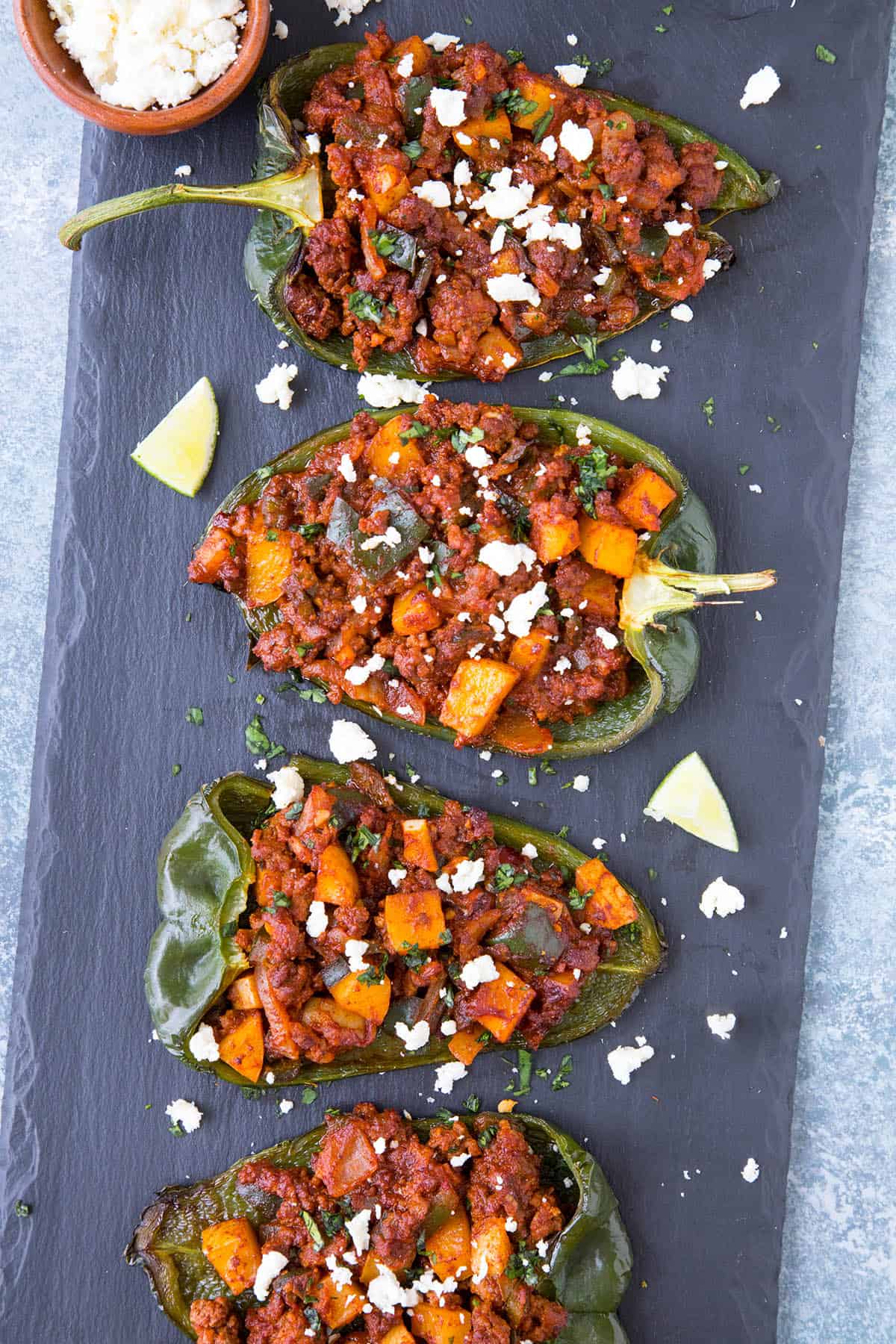 Picadillo Stuffed Poblano Peppers served on a dark board