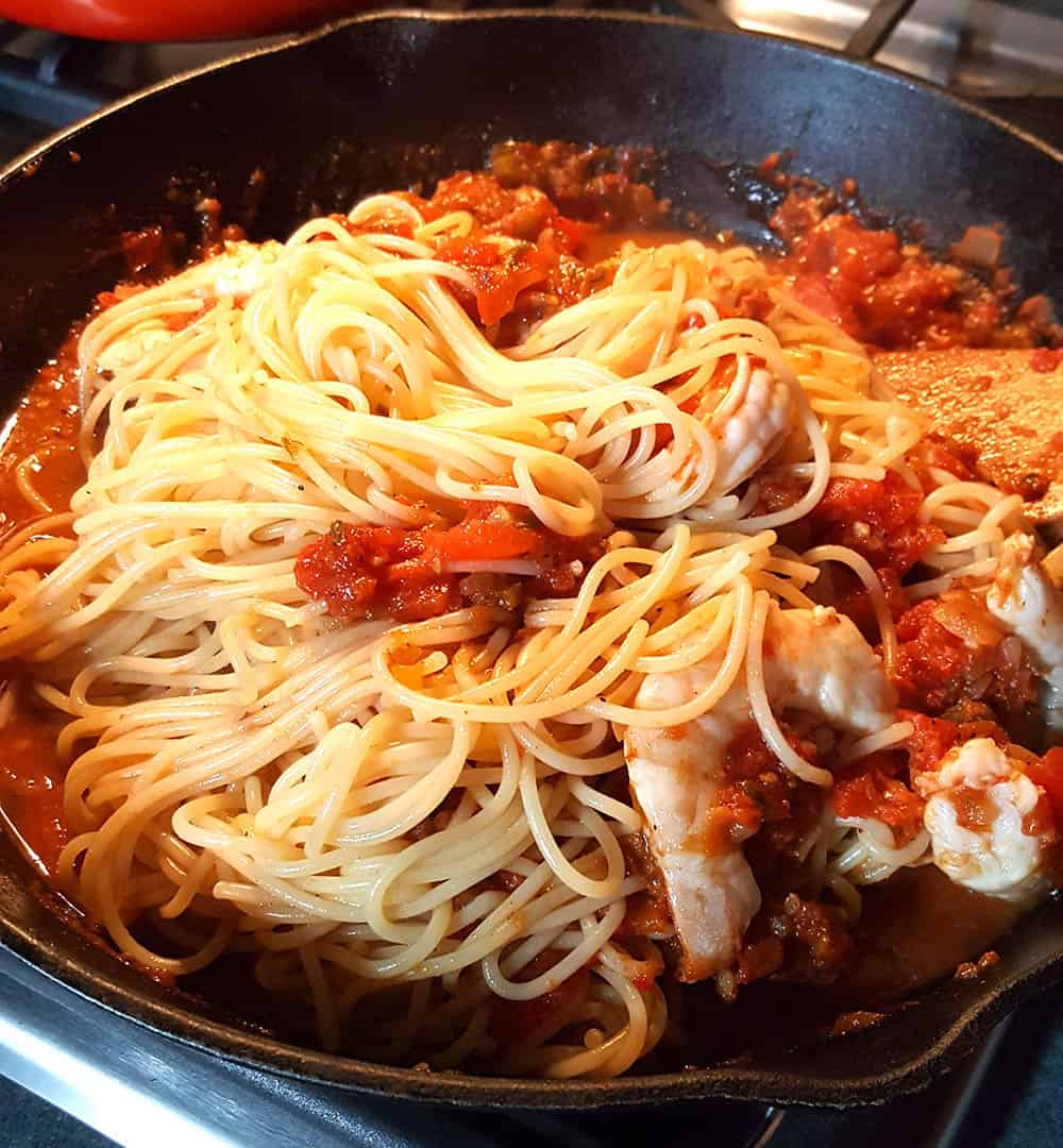 Swirling the cooked pasta into the sauce.