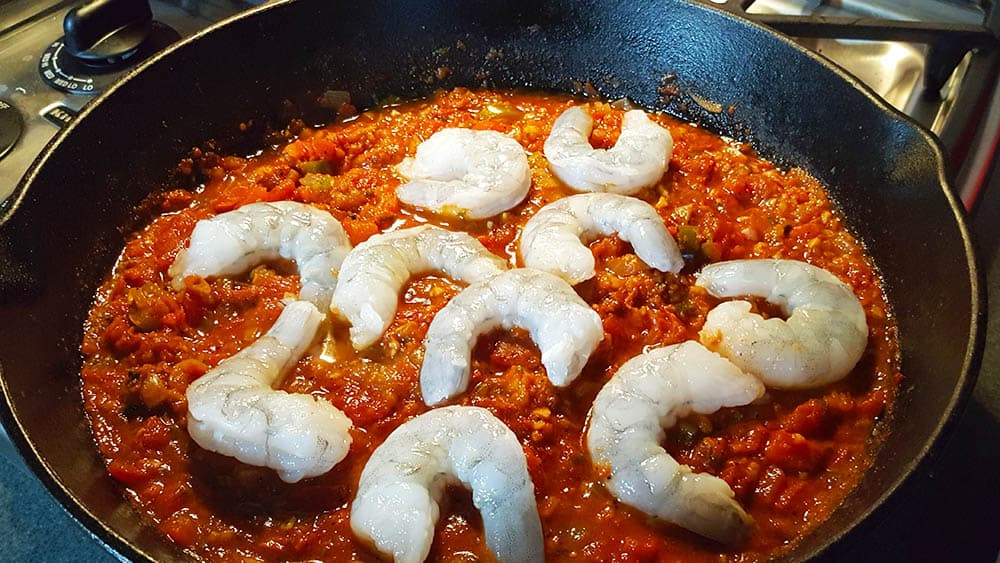 Tuck the shrimp into the pasta sauce to cook them.