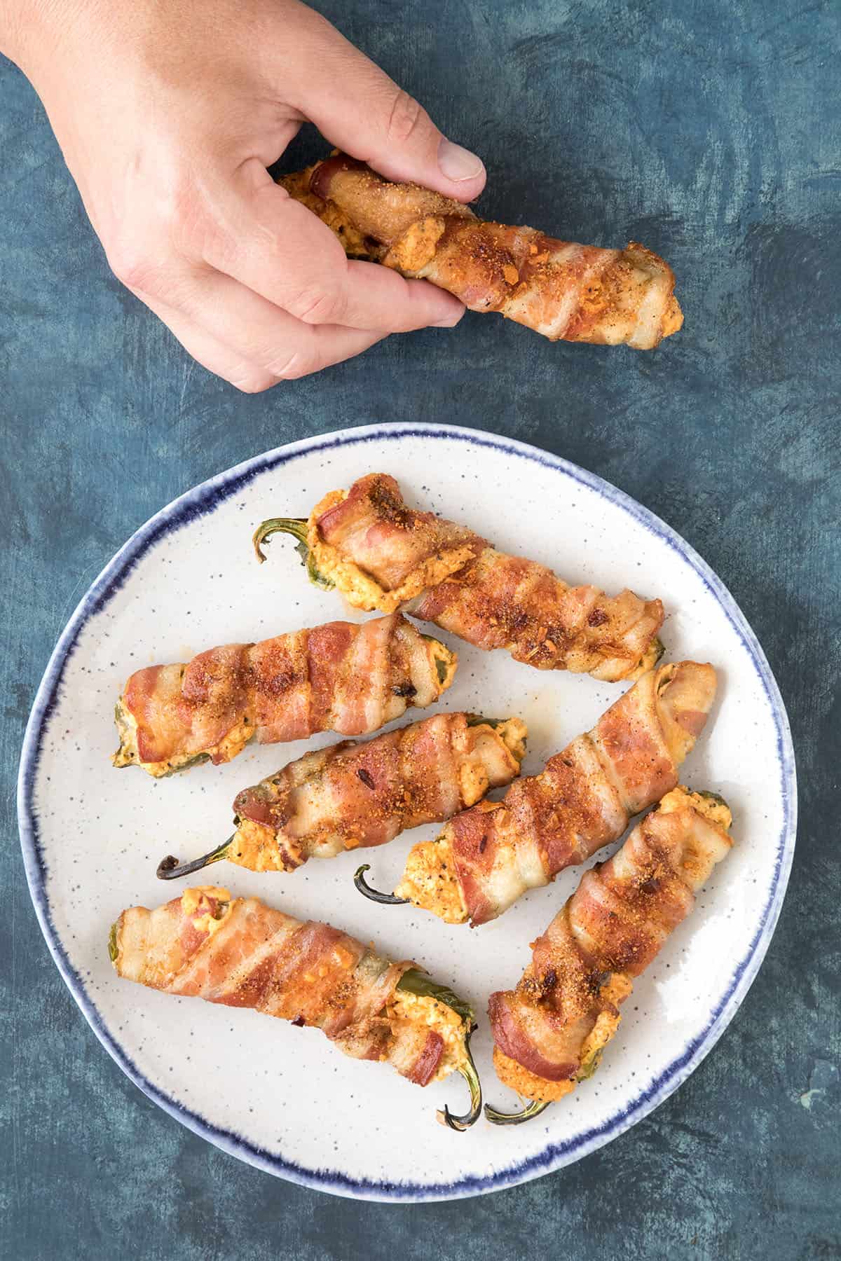 A Bacon Wrapped Jalapeno Popper in my hand, with extras plated