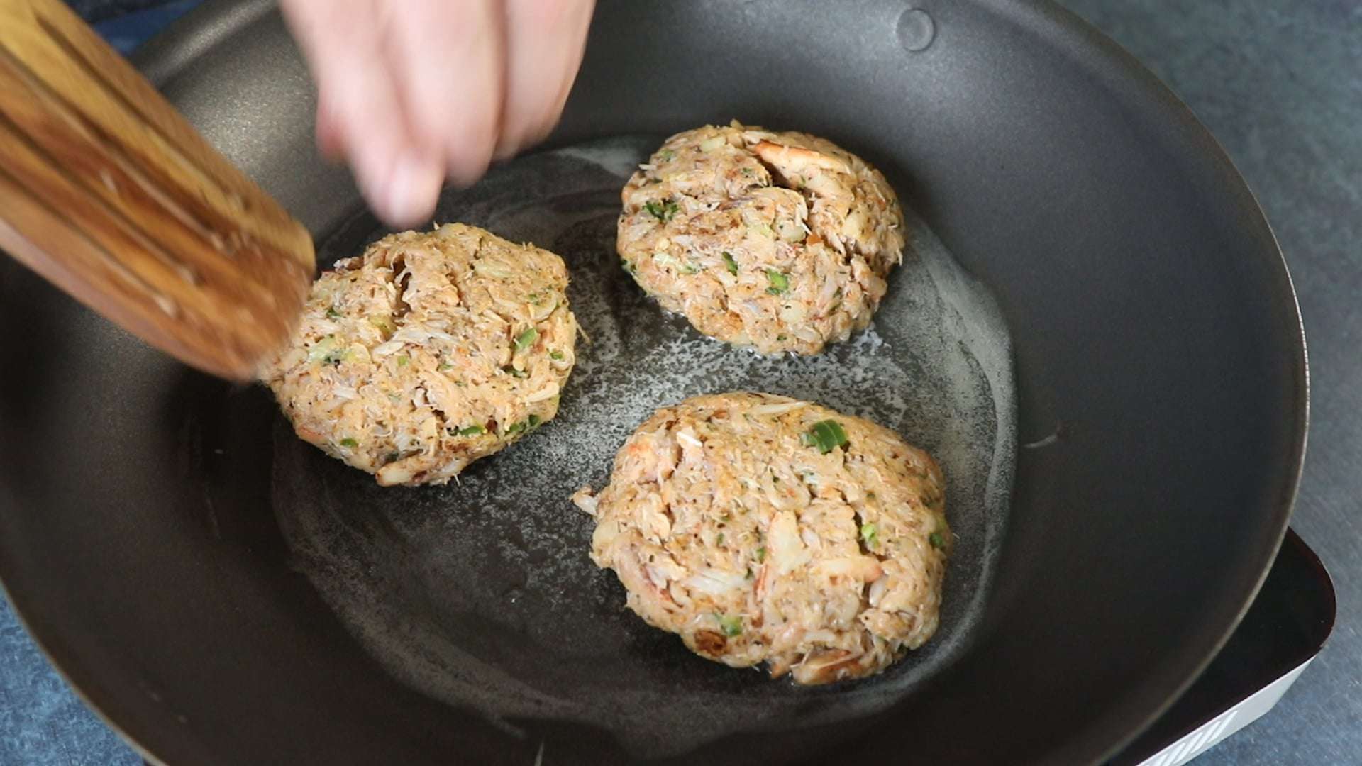 Cooking crab cakes in pan with some olive oil