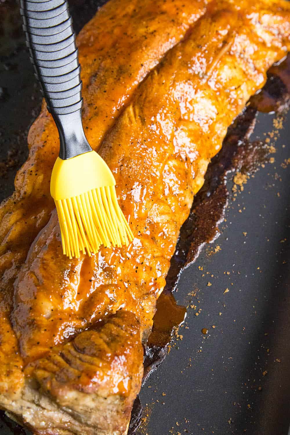 Brushing the honey-sriracha sauce on the oven baked ribs.