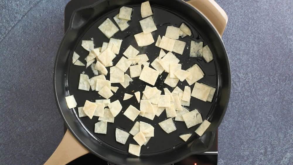 Frying tortilla strips in a pan.