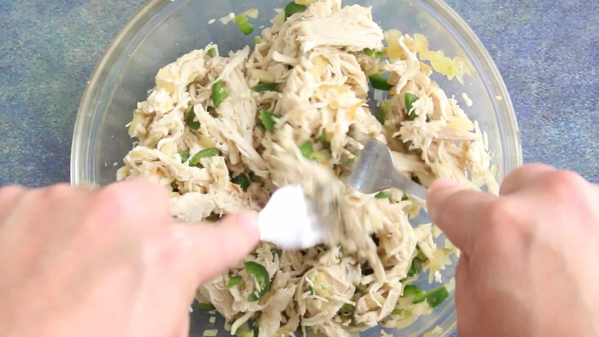 Shredding the poached chicken along with cooked peppers and onions.