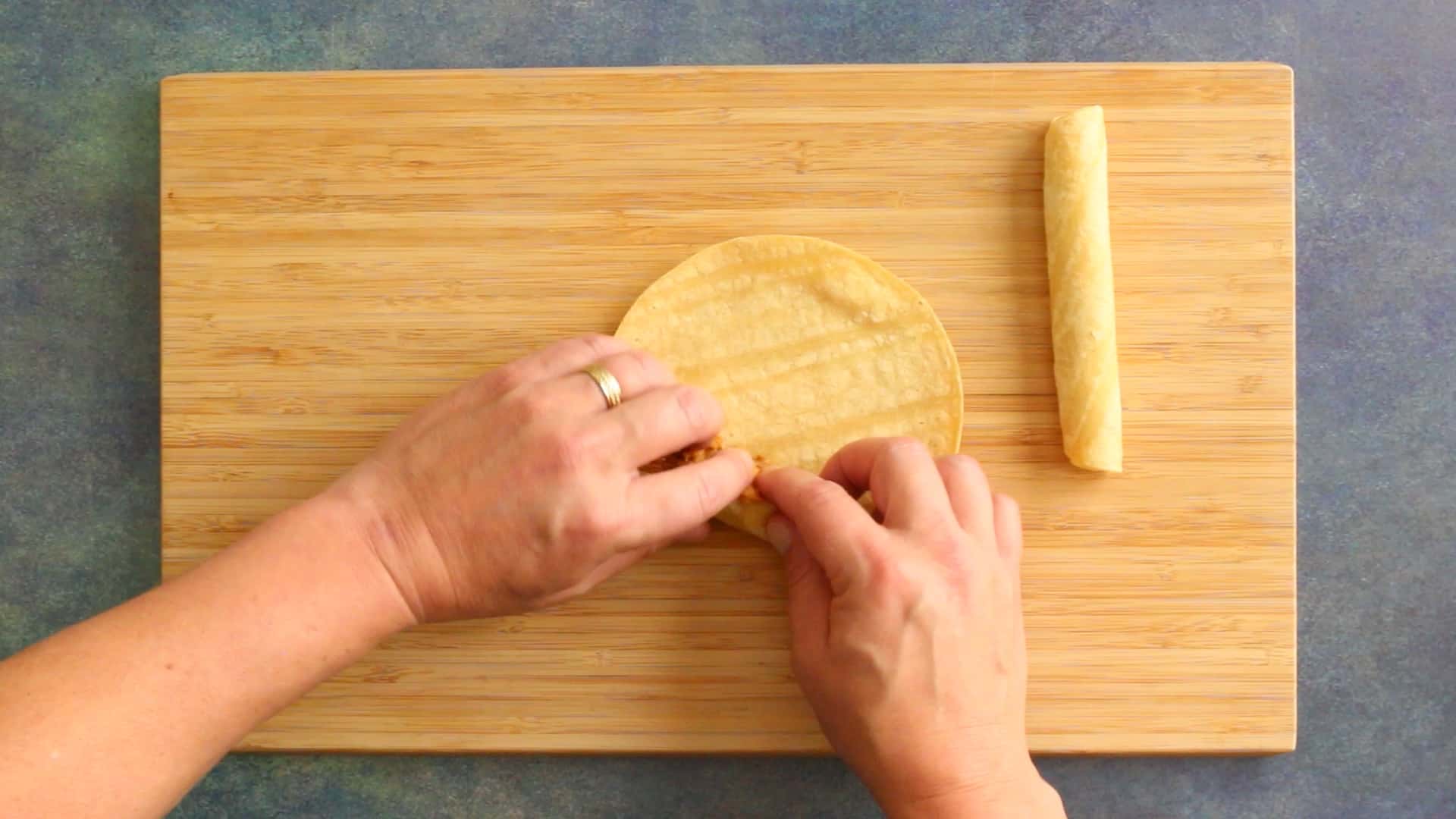 Rolling a chicken taquito in a softened corn tortilla.