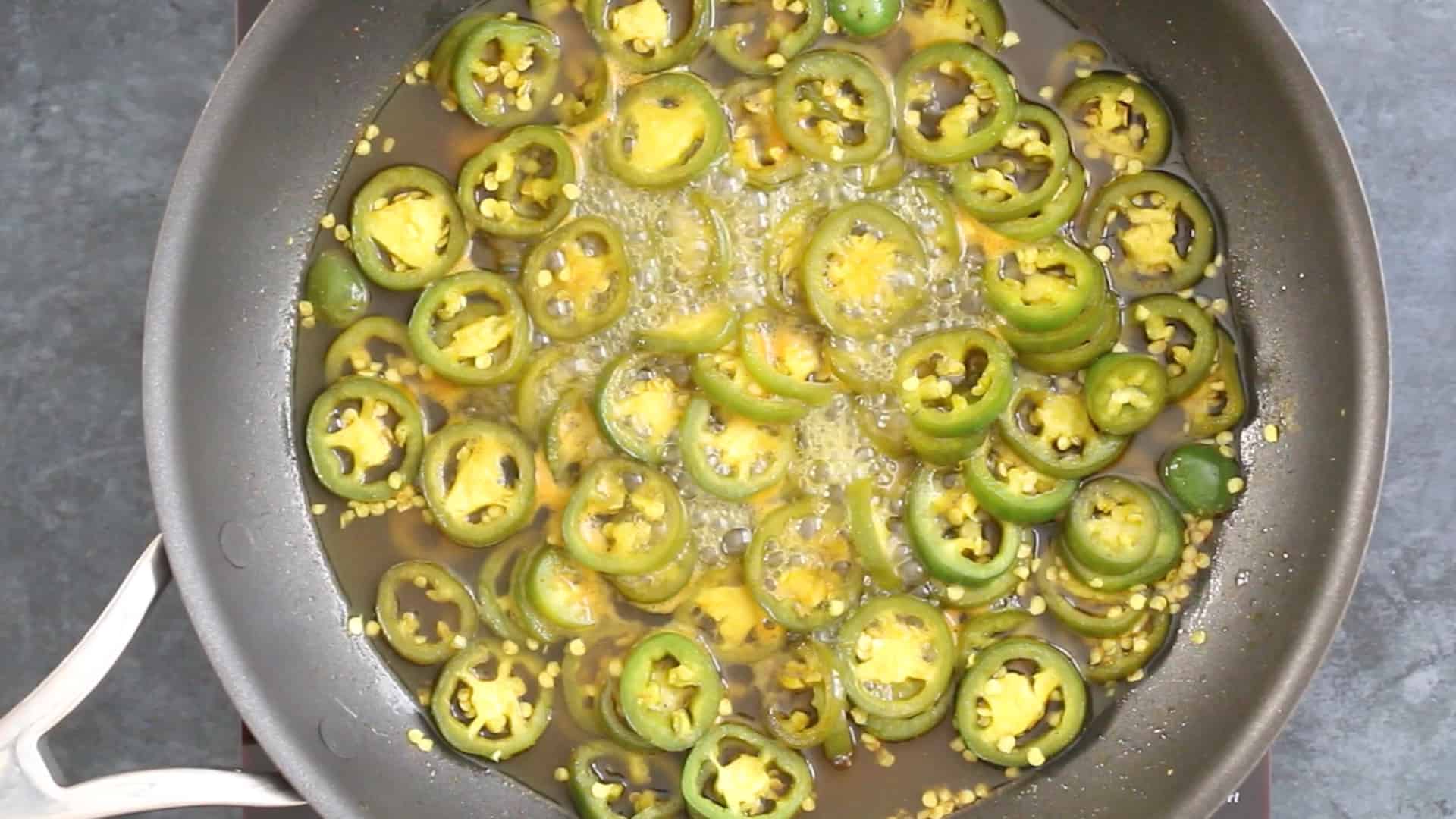 Simmering jalapeno peppers in a pan to make Candied Jalapenos (Cowboy Candy)