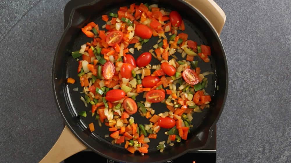 Cooked tomatoes, onion and peppers in a hot pan.