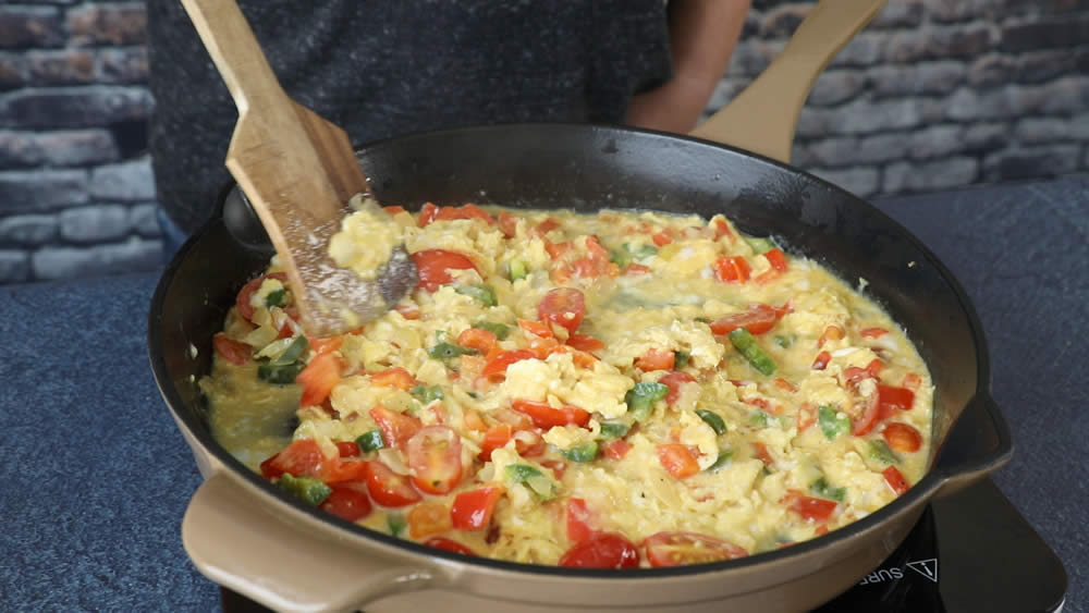 Fluffing the scrambled eggs with a spoon to make Migas.