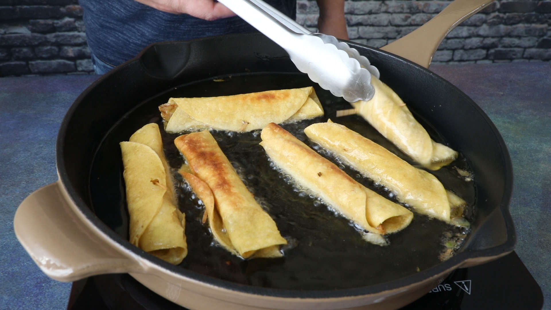 Frying the Chicken Taquitos in oil in a pan.
