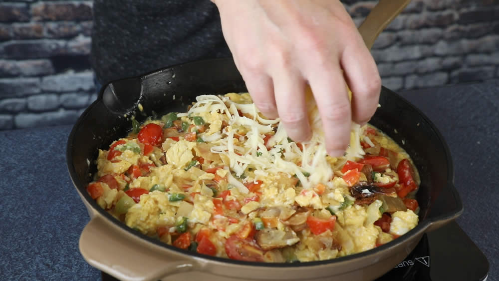 Adding cheese to our Migas dish.