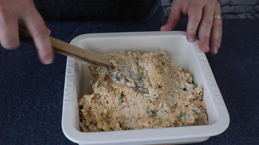 Mixing the Bacon Jalapeno Popper Dip in a casserole dish