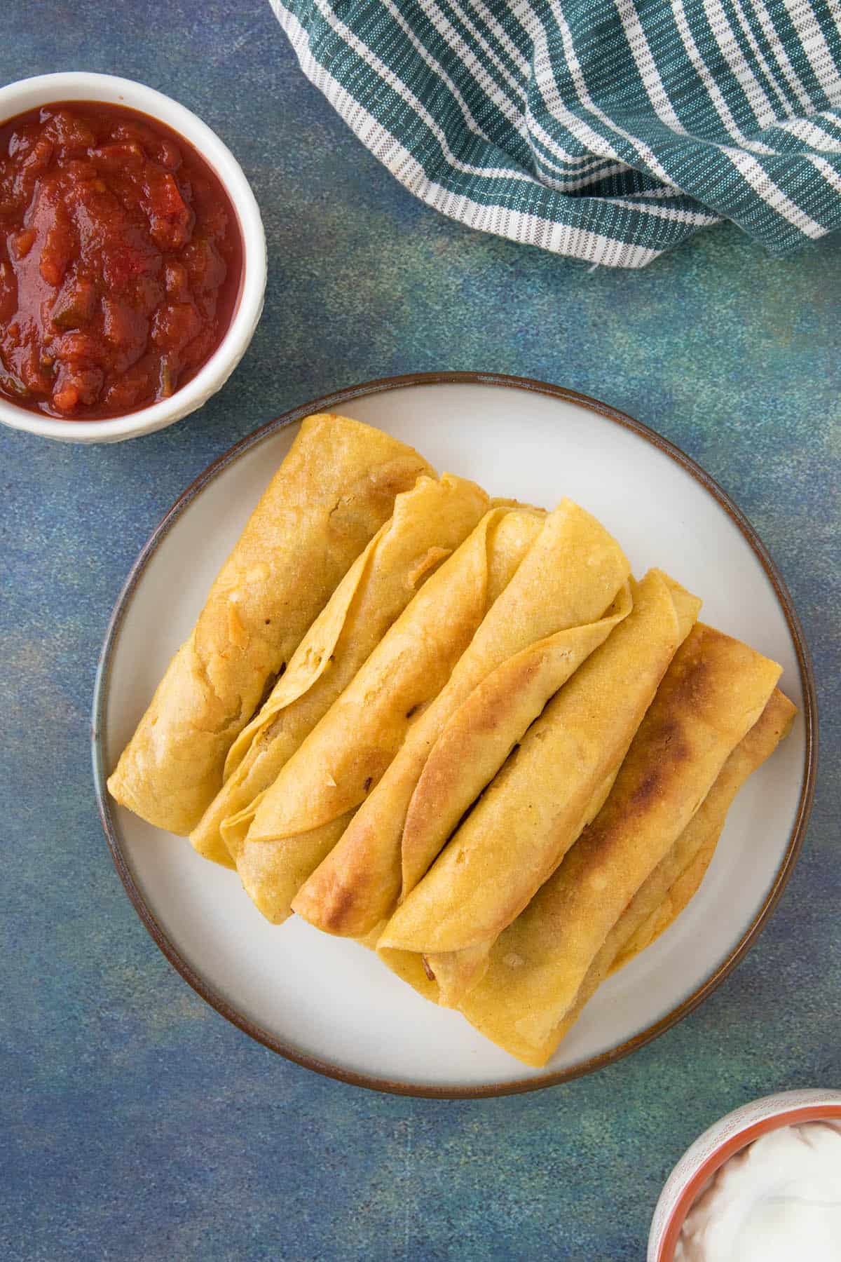 Chicken Taquitos stacked on a plate.