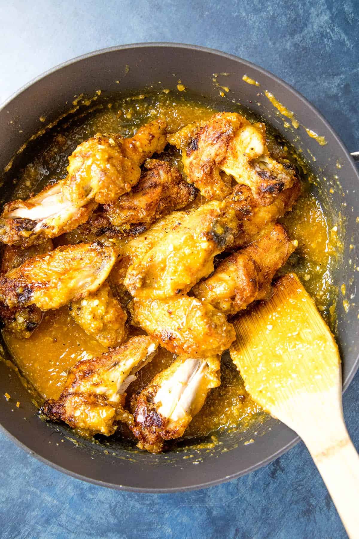 Stirring the cooked chicken wings with the mango-habanero sauce