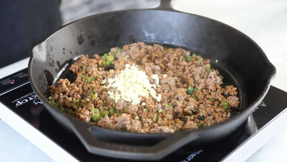 Adding fresh chopped garlic to the pan