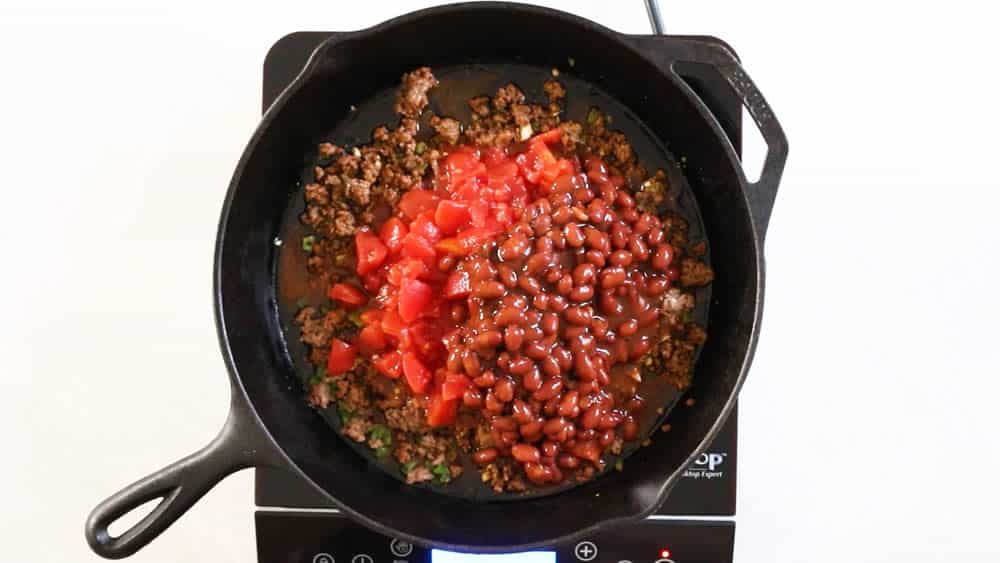 Adding tomatoes and chili beans to the pan