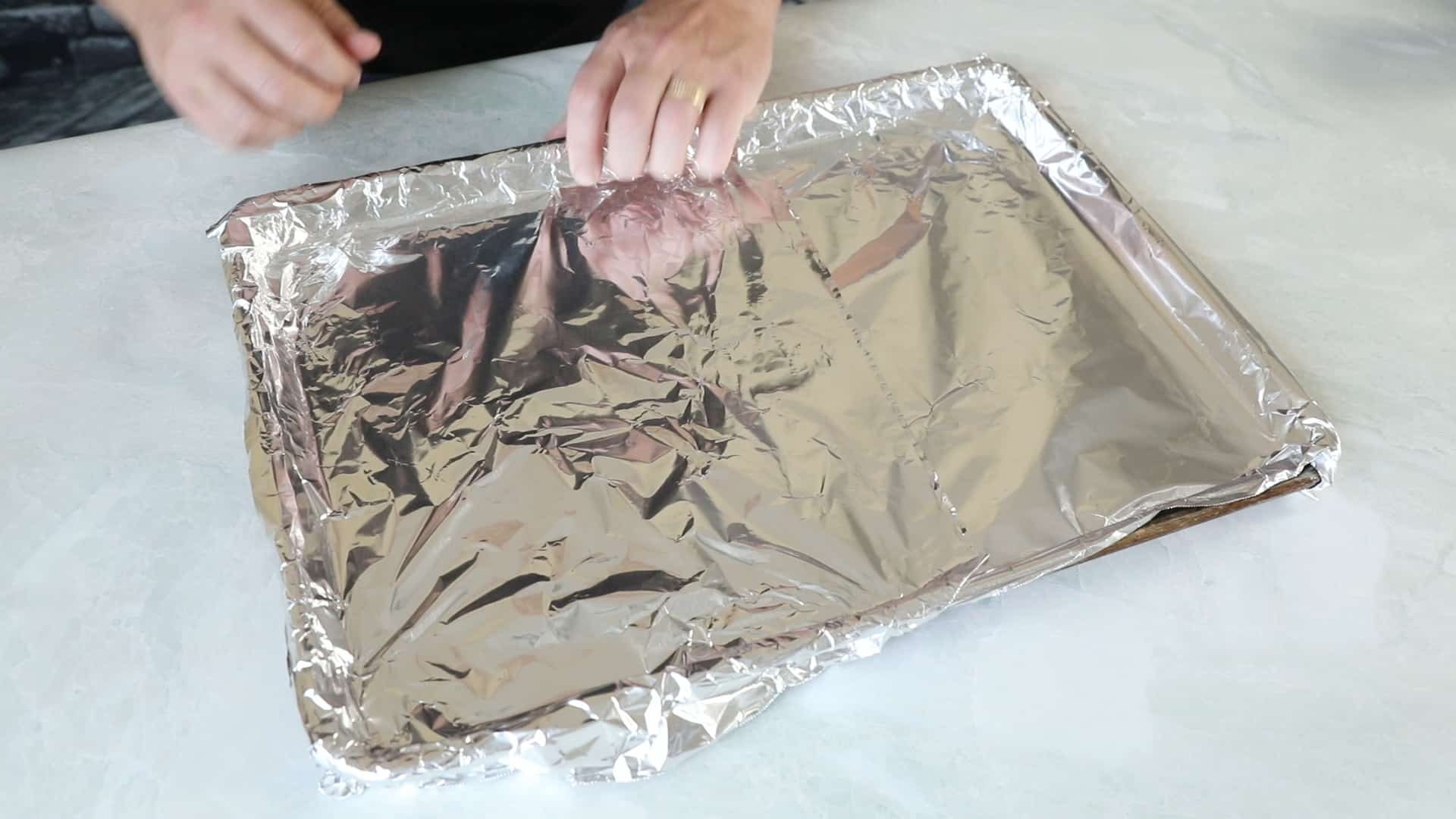 Covering a baking sheet with aluminum foil