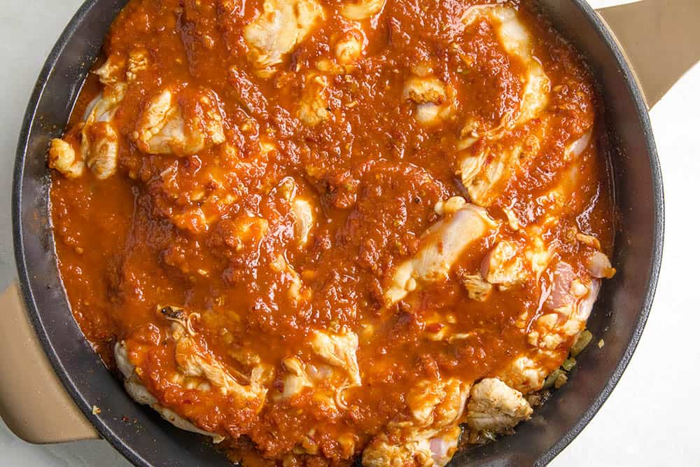 Chicken thighs simmering in our tomato-chipotle sauce for chicken tinga