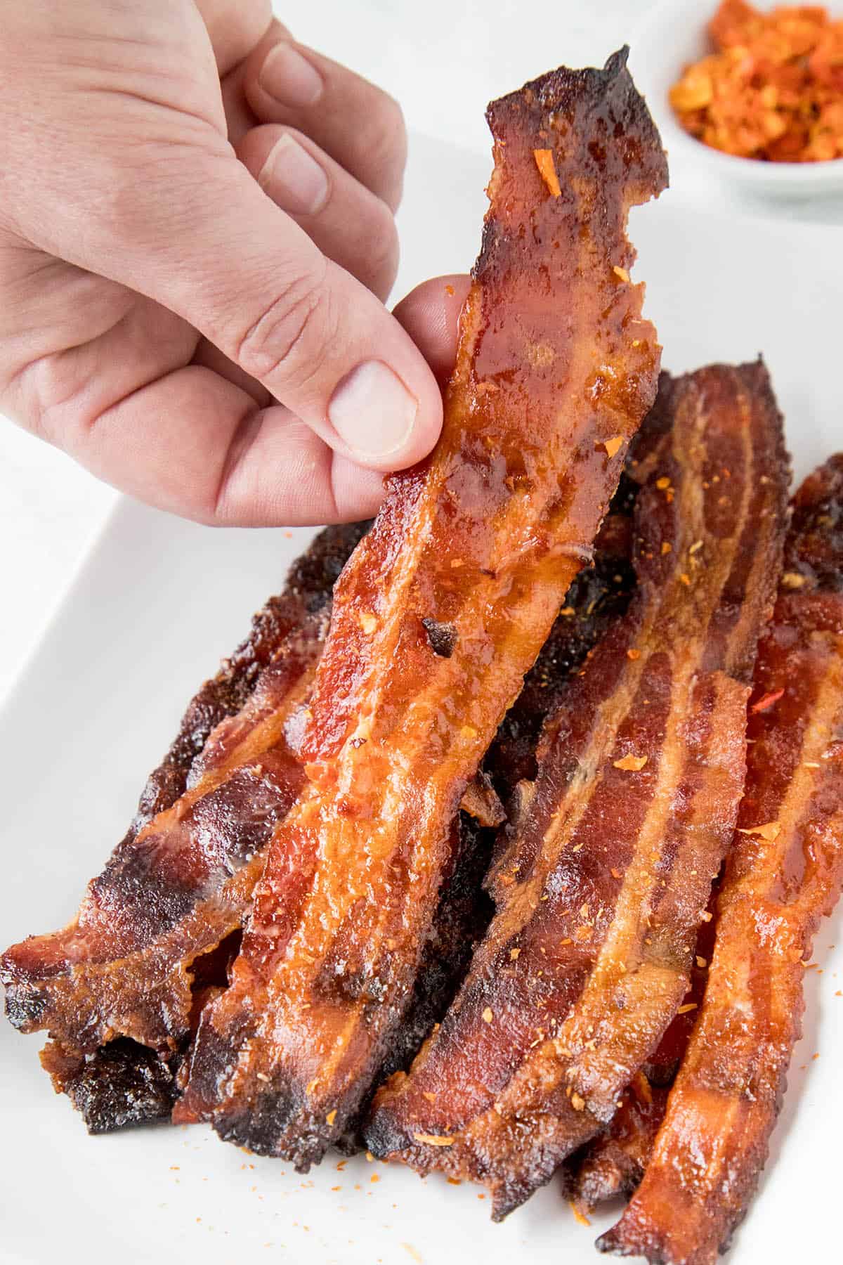 Sweet and Spicy Ghost Pepper Candied Bacon - Recipe Grabbing a piece of Ghost Pepper Candied Bacon