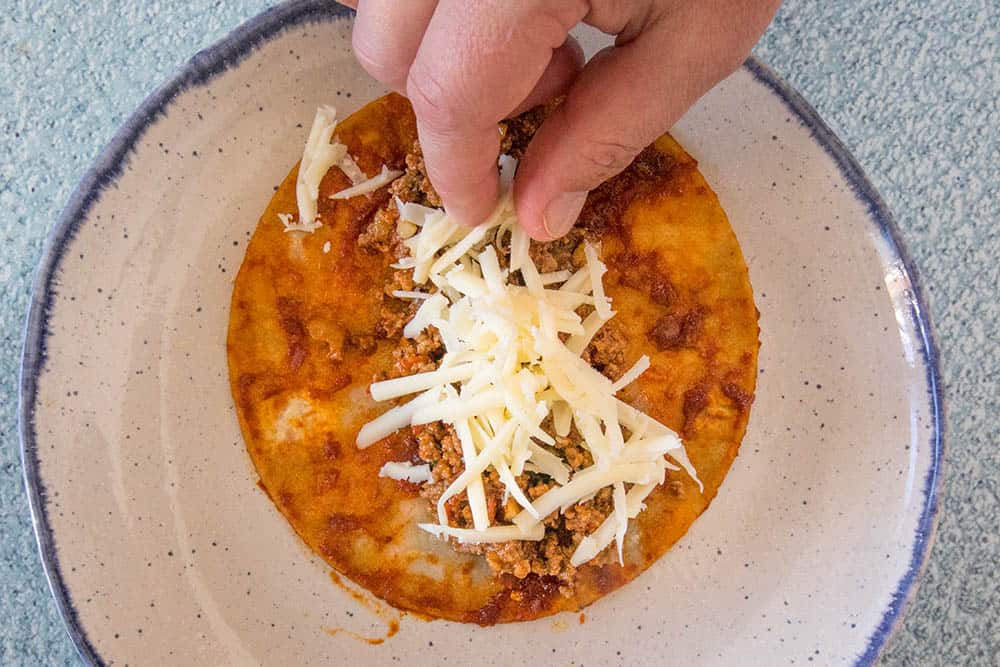 Placing cheese on the dipped corn tortilla