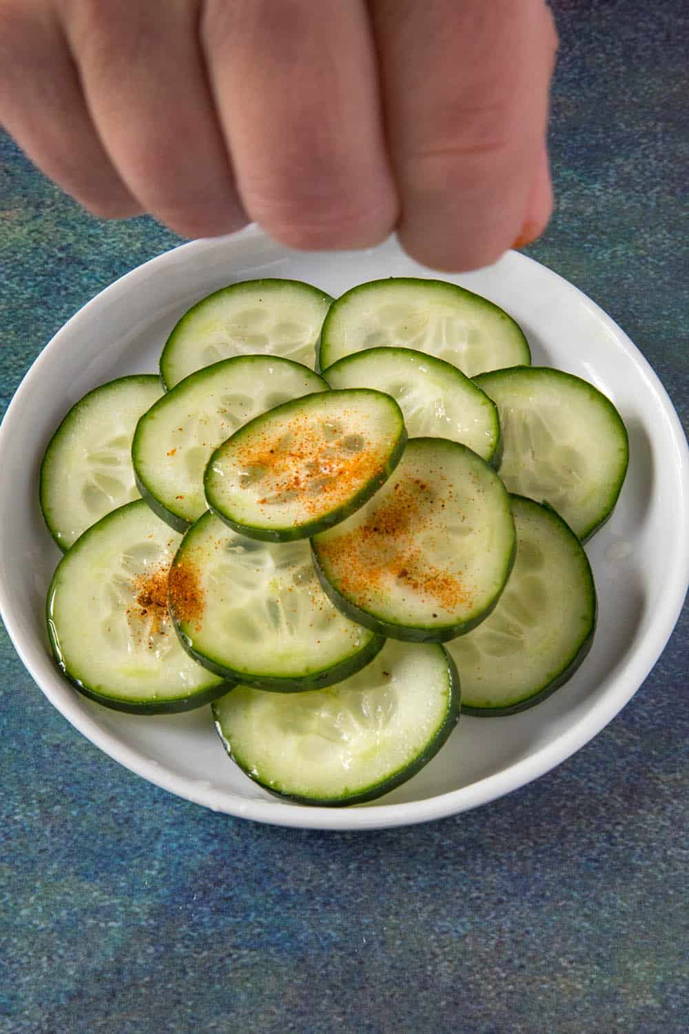 Sprinkling chili powder over the cucumber slices