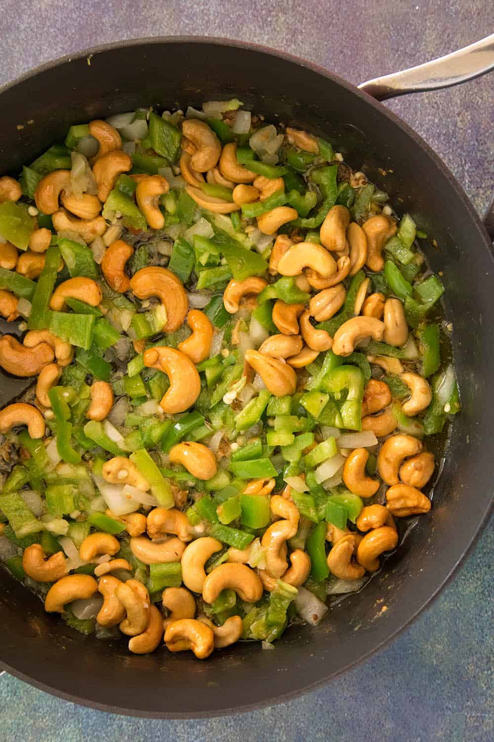 Cooking down the onions, peppers and cashew nuts