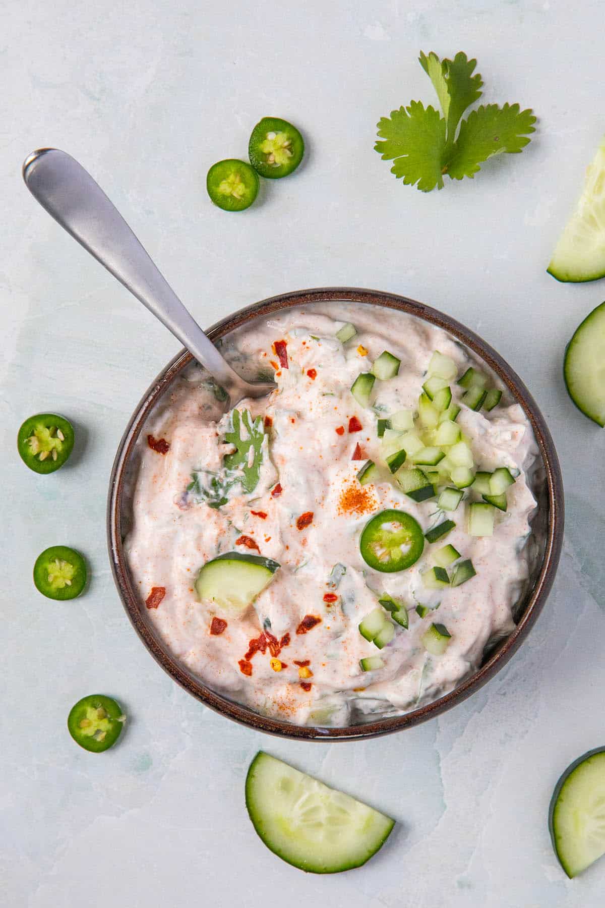 Indian Raita in a bowl, garnished with cucumbers and serrano slices