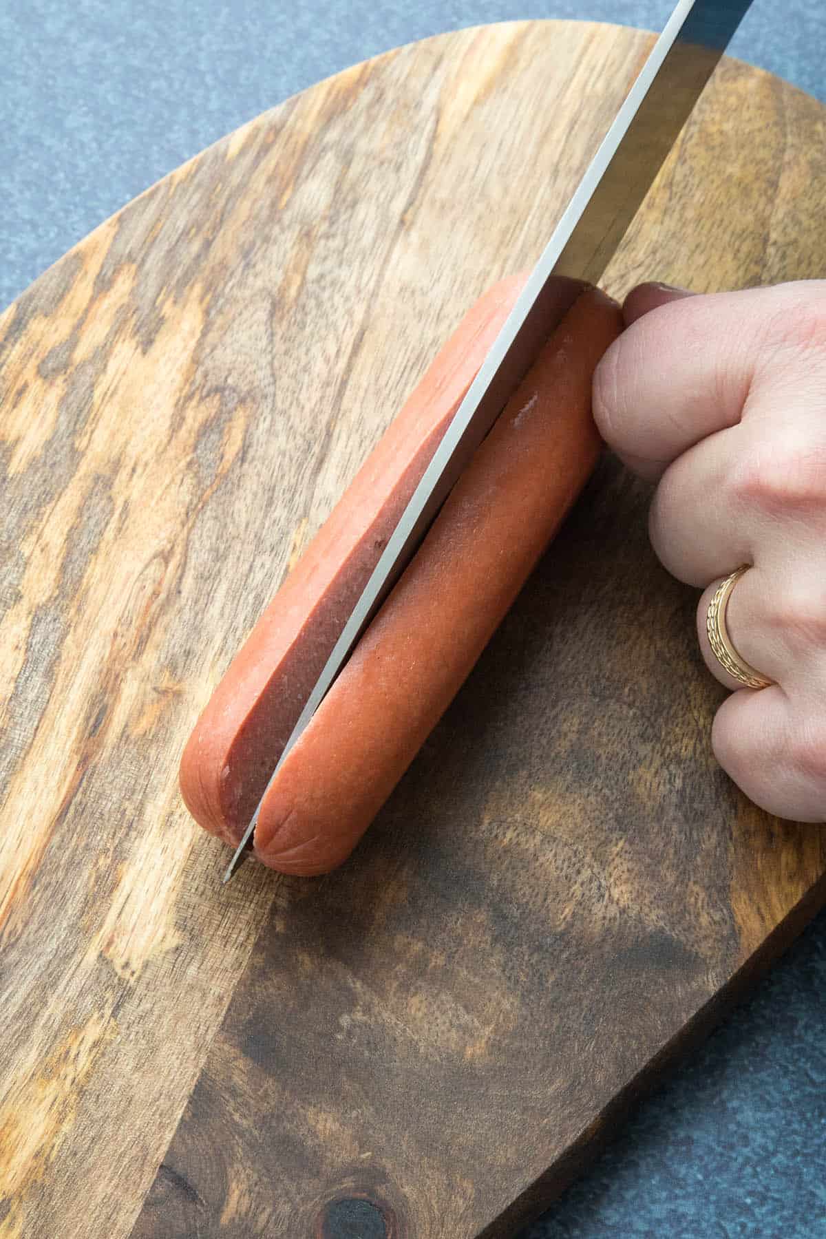 Slicing an all beef hot dog open to make Chicago style char dogs.