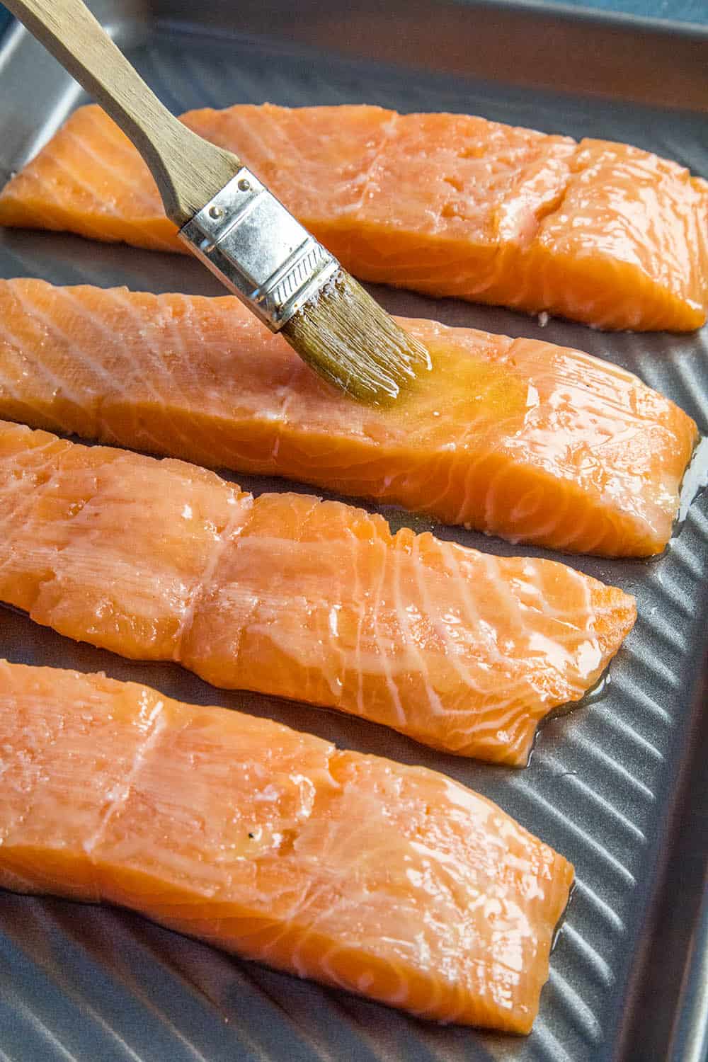 Buttering the salmon before seasoning them