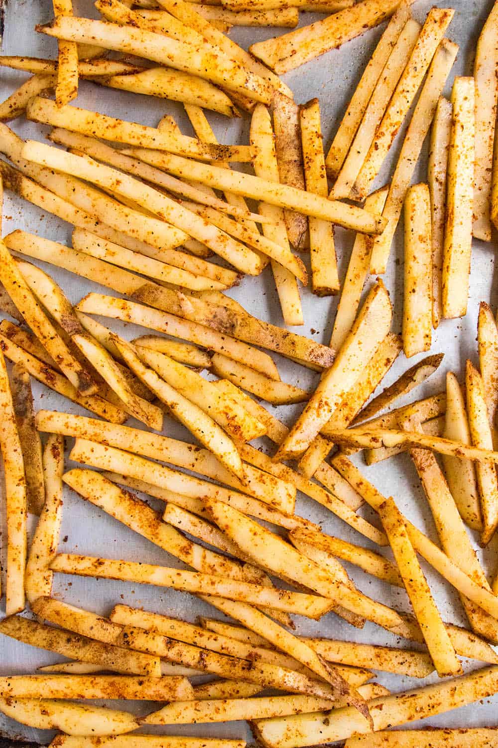 Seasoned potato slices on a baking tray