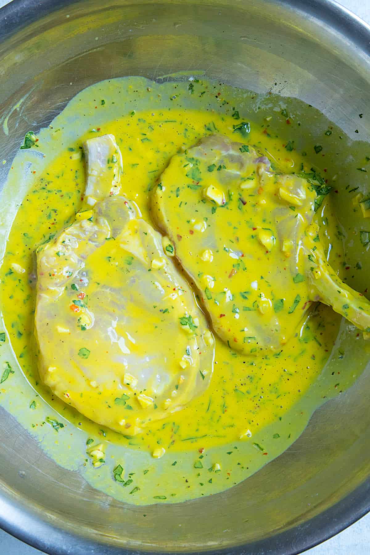 Pork chops marinating in a bowl