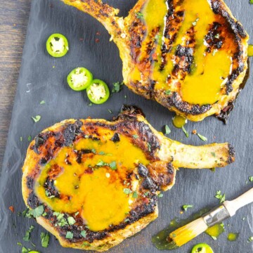 Grilled Pork Chops with Carolina Mustard BBQ Sauce on a platter, drizzled with sauce