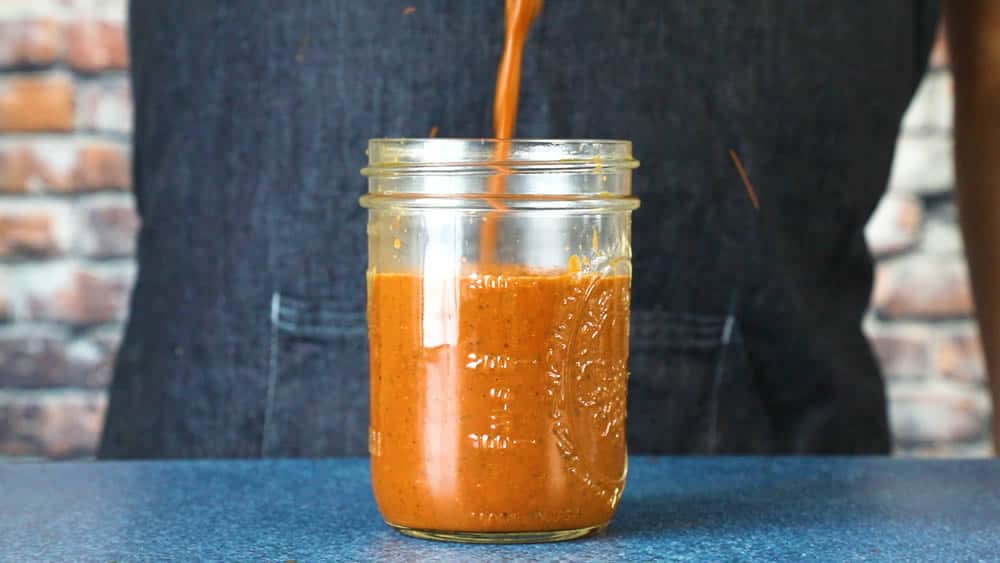 Pouring the ranchero sauce into a jar