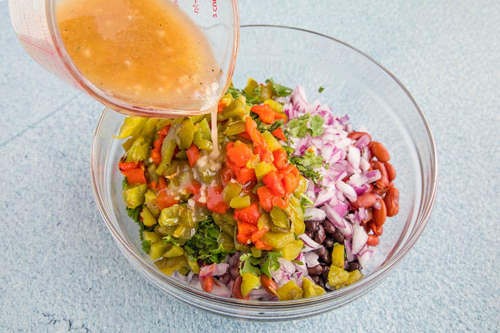 Pouring the vinaigrette into the bowl with the other ingredients