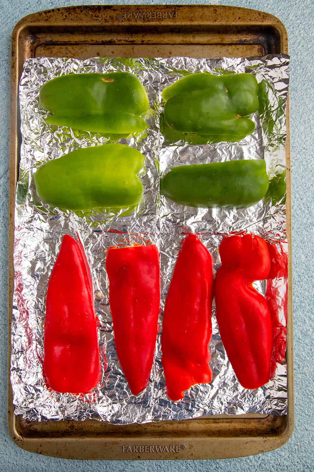 Peppers on a baking sheet, ready to roast in the oven